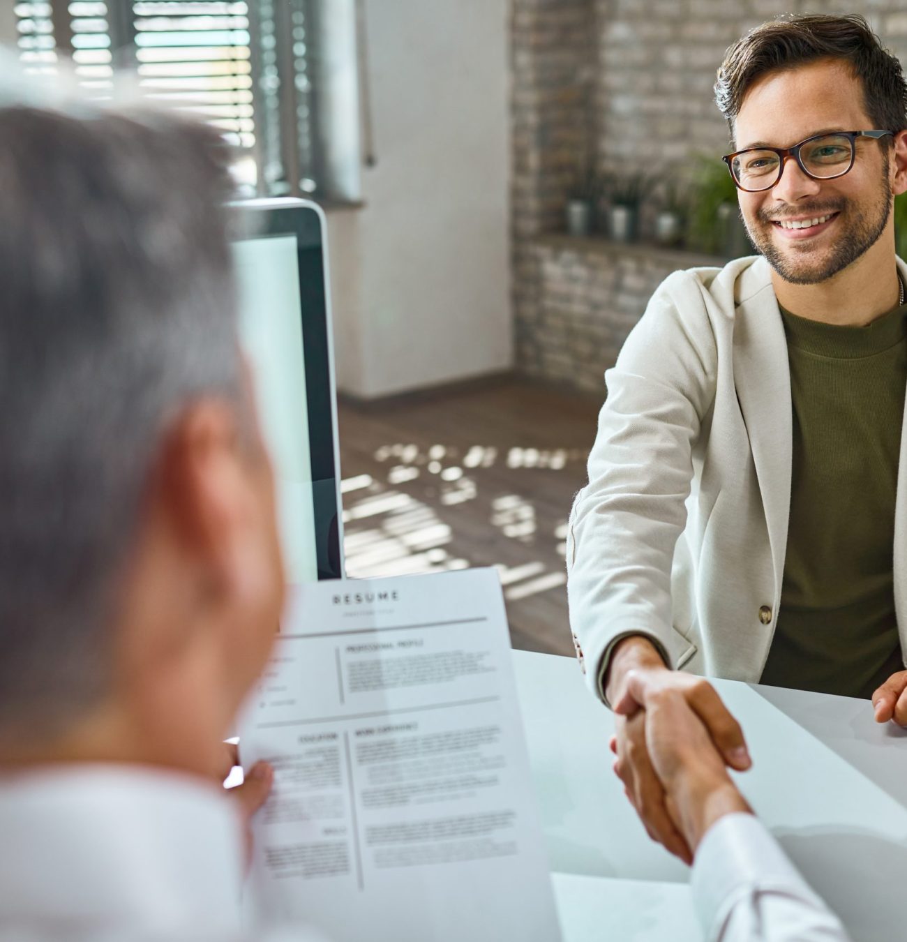 Happy male candidate greeting a member of human resource team on a job interview in the office.